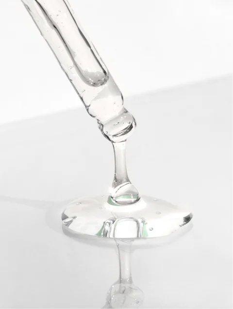 Eclat Soin Caffeine Gel Booster being dispensed from a dropper, showcasing its clear and smooth consistency